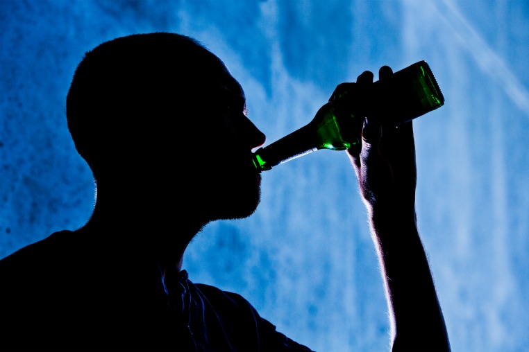 A man is seen drinking from a beer bottle