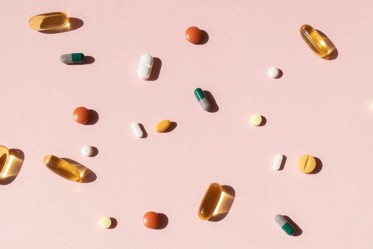 Top view of various pills and tablets on the pink background