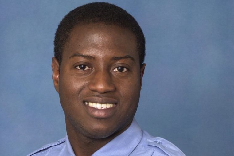 Sorffly Davius smiles for a portrait against a blue background