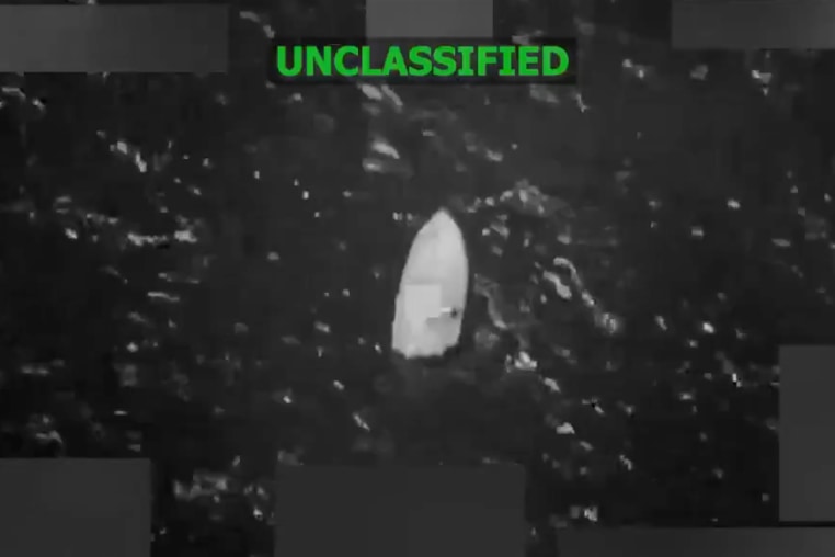 A grainy black-and-white still image taken from video shows a boat floating in the water.