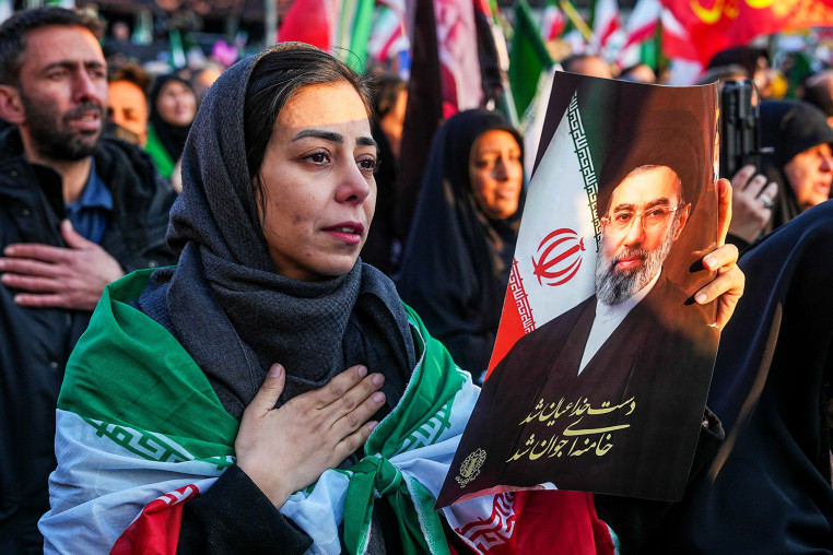 Image: A woman holds a picture of Iran's new Supreme Leader Ayatollah Mojtaba Khamenei