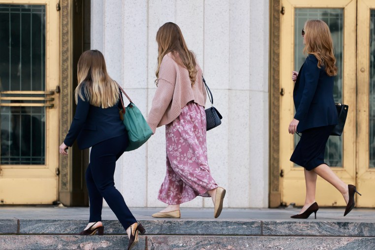 Three women are seen in profile view as they ascend the stone steps to a courthouse.