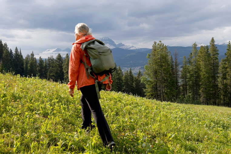 Image: Mature woman hiking through a mountain meadow