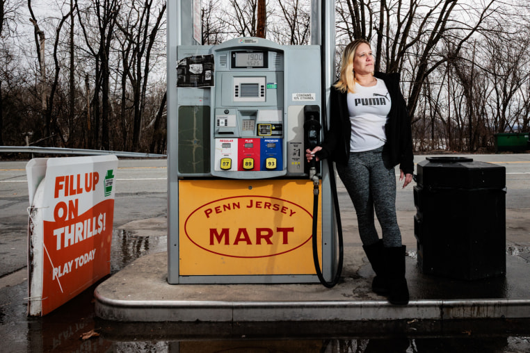 Amanda Robbins holds a gas pump at a gas station while posing for a portrait