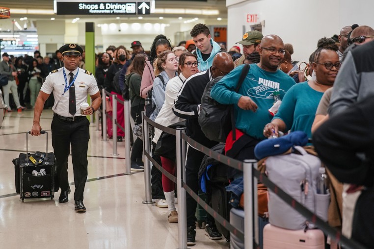 A pilot walks past travelers waiting in line at a Transportation Security Administration (TSA) checkpoint at Hartsfield-Jackson Atlanta International Airport (ATL) in Atlanta, Georgia, US, on Friday, March 20, 2026.