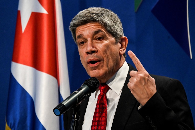 Carlos Fernández de Cossío speaking in front of a Cuban flag.