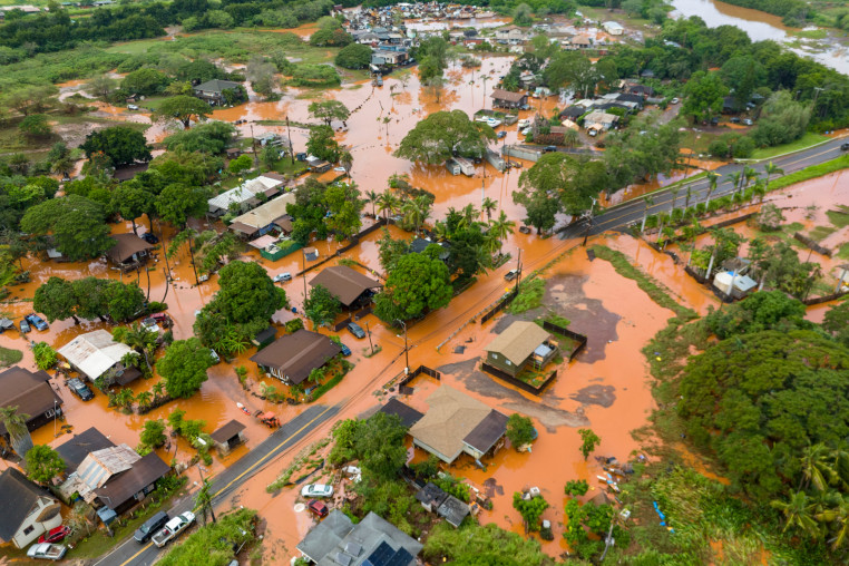 Brown floodwater covers much of a residential neighborhood, seen from an aerial perspective