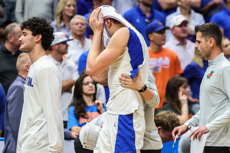 A basketball player hides his head inside his jersey while walking on the court.