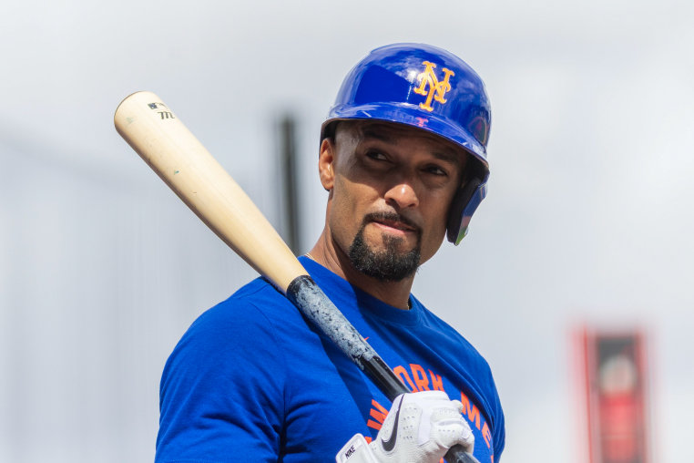 Marcus Semien looks over his shoulder while wearing a helmet and holding a baseball bat. 