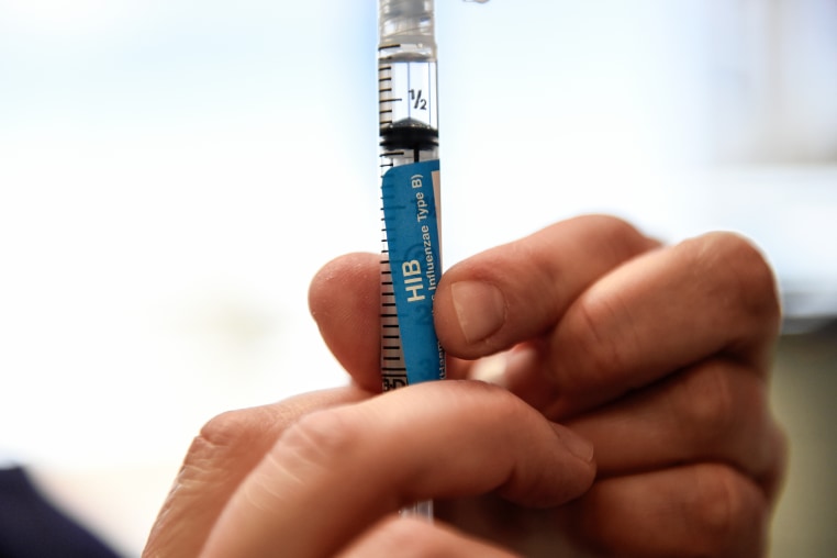A detail of a syringe containing an Hib vaccine.