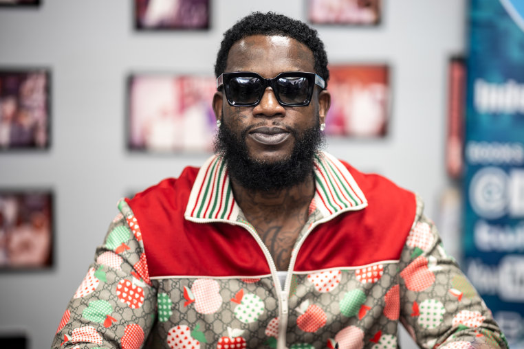 Gucci Mane is seated and wearing dark sunglasses.