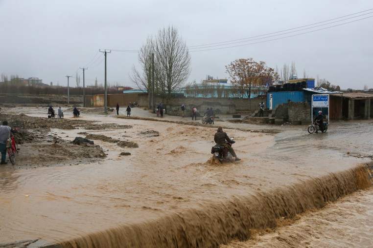 An Afghan motorist wades across a flooded road during rainfall in Ghazni Province on April 1.
