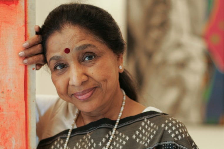 Asha Boshe leans up against an entryway and smiles for a portrait