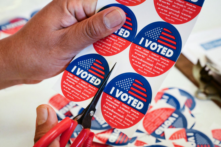 Close up on a sheet of "I Voted" stickers being cut on a table