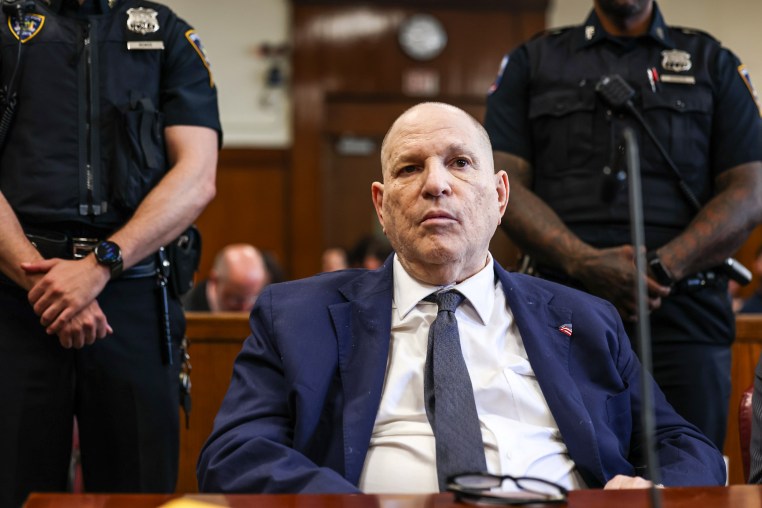Harvey Weinstein sits at a table in court