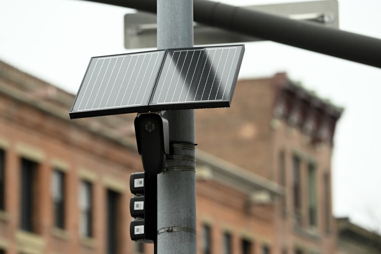 A solar-powered surveillance camera mounted on a light pole.