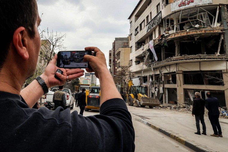 A man films with a phone from the street the destruction on an office building