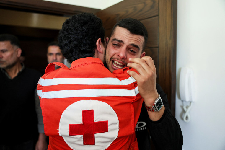 Colleagues of Red Cross paramedic Hassan Badawi, who was killed in an Israeli strike on Sunday, mourn following his funeral, in Bechamoun