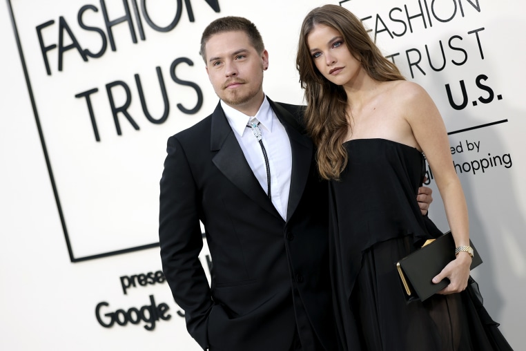 Dylan Sprouse and Barbara Palvin stand for photos in front of a step-and-repeat backdrop.