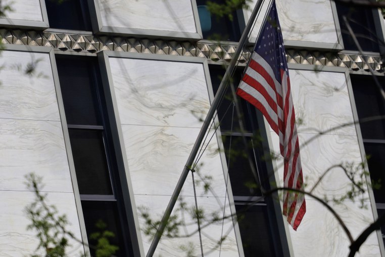 The American flag is displayed outside a non-descript marble building with slender tinted windows.