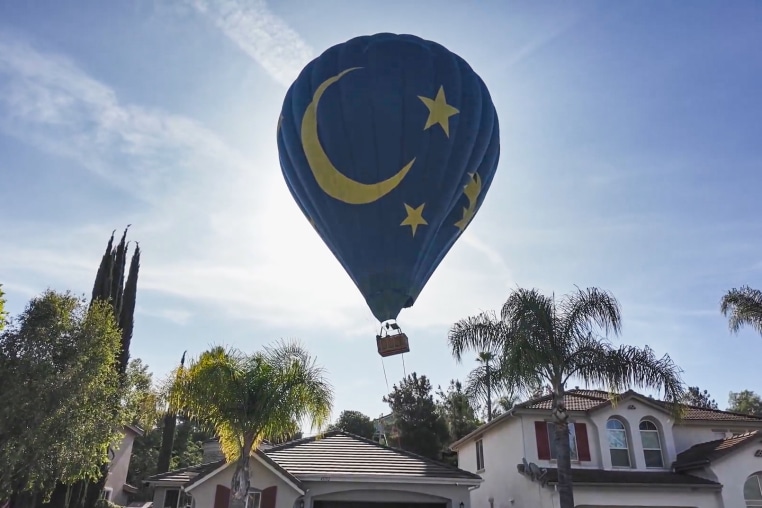 A hot air balloon in the sky above a house