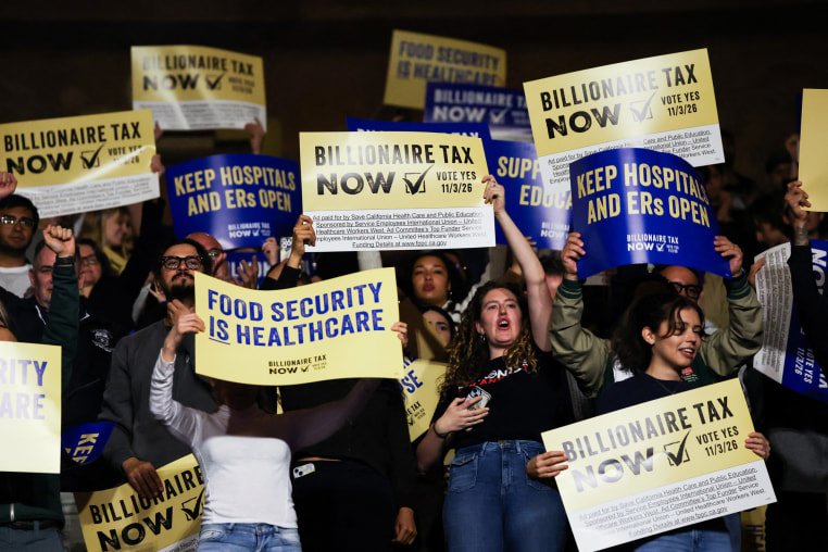 People hold posters in favor of the billionaire tax act