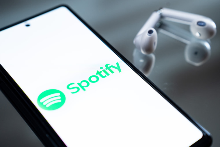 The Spotify logo appears on a smartphone screen.