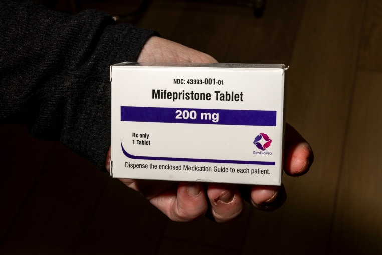 A hand holds a box of mifepristone
