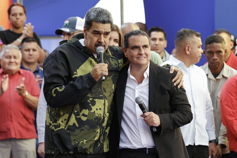 Nicolas Maduro and Alex Saab stand together with microphones in a crowd.