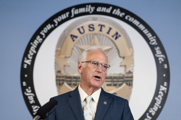 Kirk Watson speaks during a press conference in front of the seal of the AUstin Police Department.