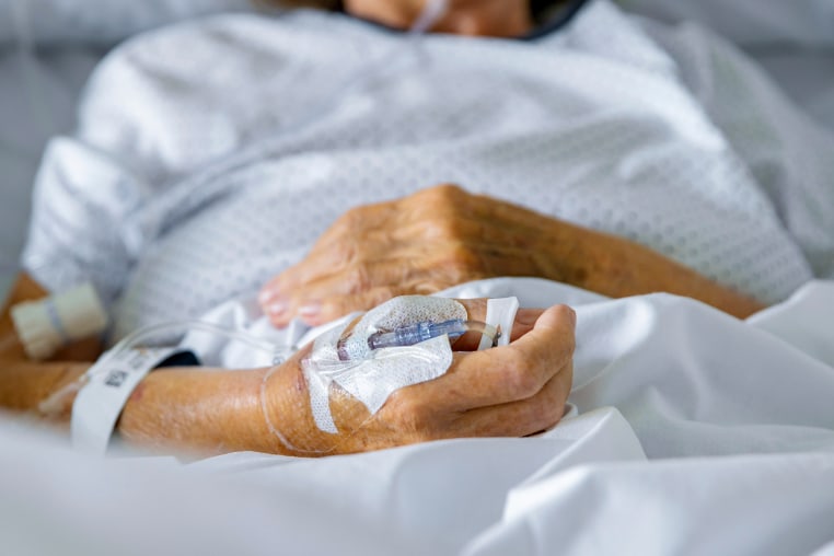 Unrecognisable elderly female patient in hospital bed with Pulse Oximeter on finger.