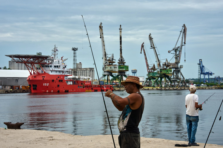A fisherman prepares his fishing rod in front of the Colombian Navy ship ARC Carib in Havana.