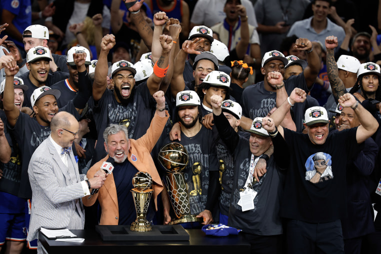 New York Knicks players celebrate while standing with their coach during an after-game press conference.