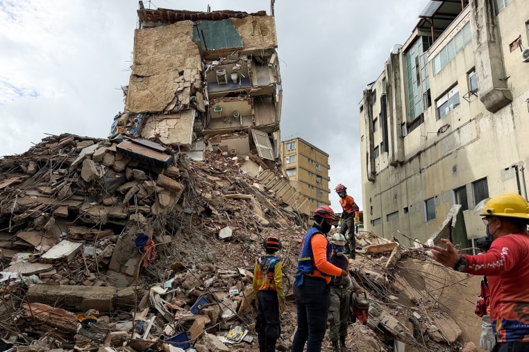 Workers search for people amongst the rubble of an apartment building