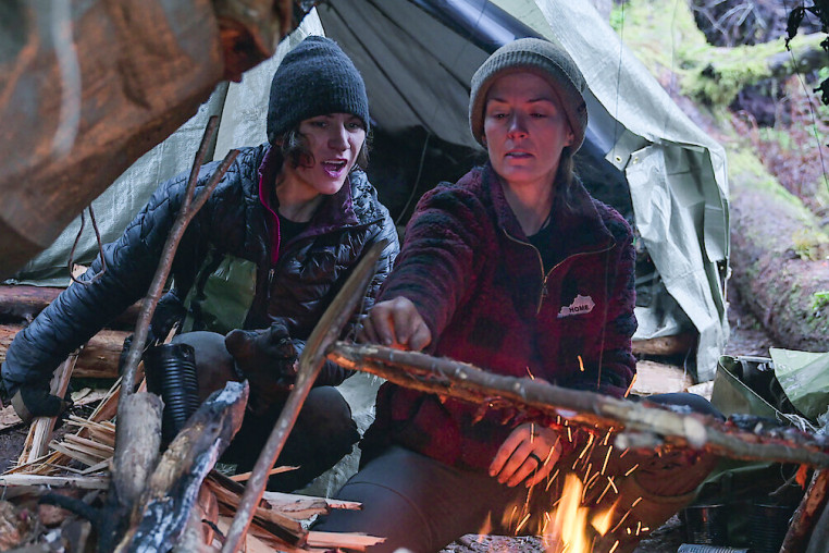 Amber Asay, left, and Jill Ashock light a fire outside while sitting underneath a tent