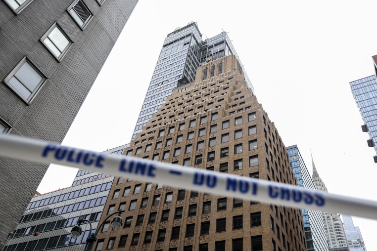 White tape with blue lettering reading POLICE LINE - DO NOT CROSS stretched in front of high-rise buildings in downtown Manhattan.