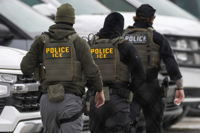 ICE agents walk in line.