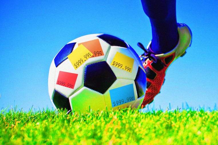 A foot going to kick a soccer ball on grass against a blue sky; the soccer ball is covered in price stickers.