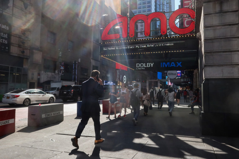 People walking past an AMC Movie Theater in Times Square in New York City.