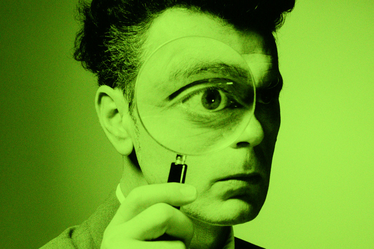 A man holding a magnifying glass to his eye.