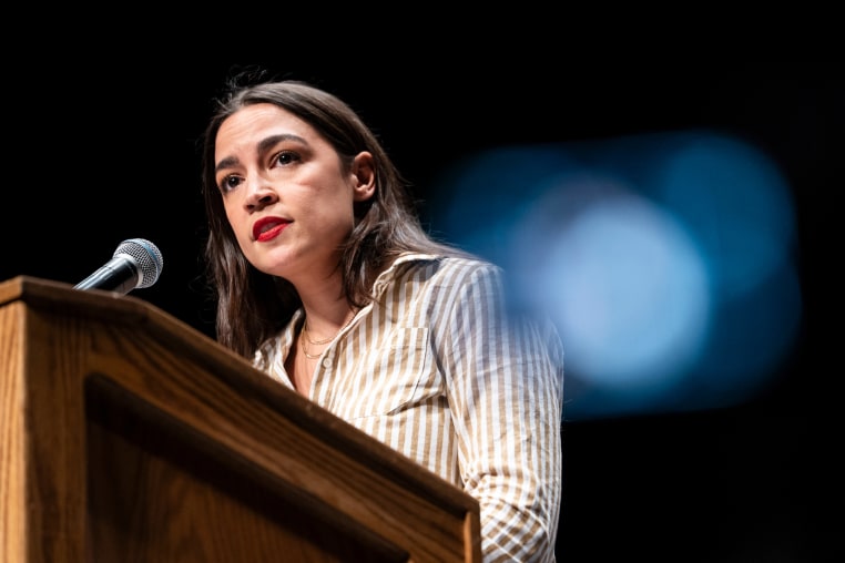 Alexandria Ocasio-Cortez speaks at a podium onstage