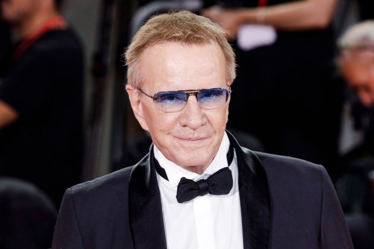Christopher Lambert stands for a portrait wearing sunglasses, a black suit and black bowtie