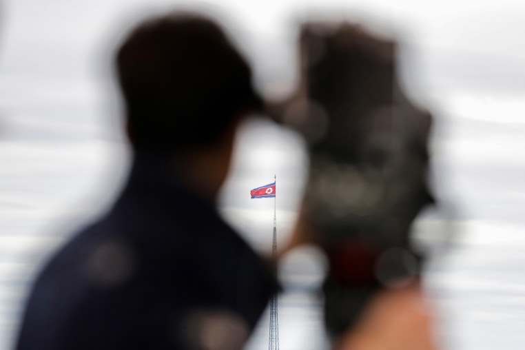 A North Korean flag flutters in the wind as seen from afar.