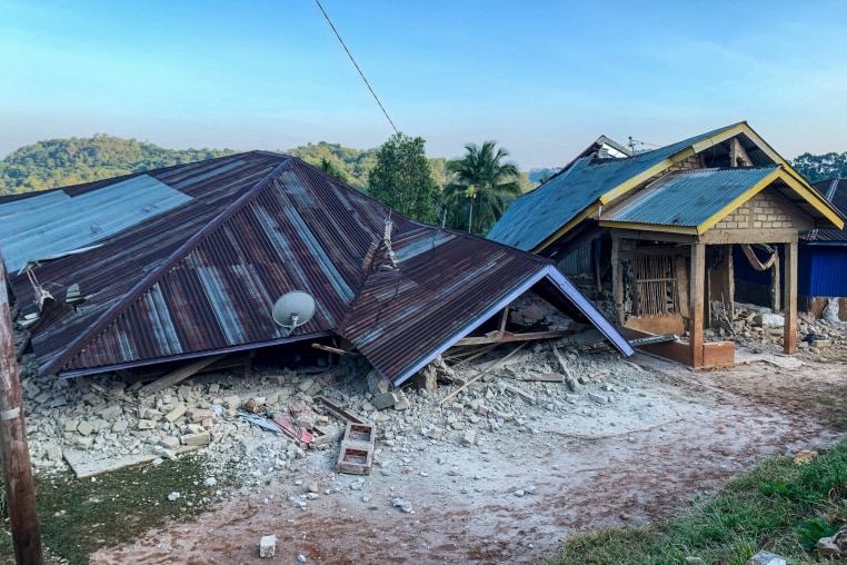 Collapsed houses are seen in daylight.