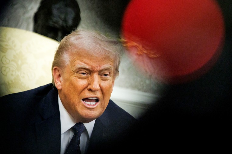 President Donald Trump speaks; a red dot of light hovers near his head