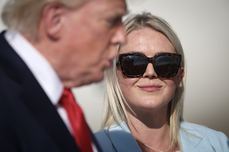 Donald Trump appears in soft focus in front of Karoline Leavitt.
