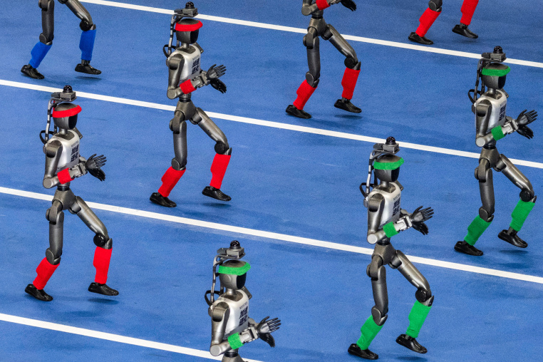 Humanoid robots walk in procession on a blue track