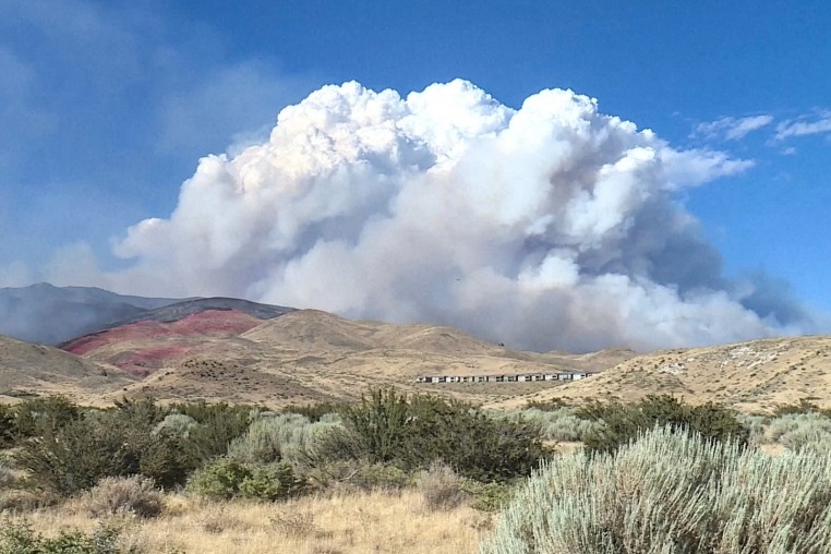 A cloud of smoke can be seen over a mountainscape