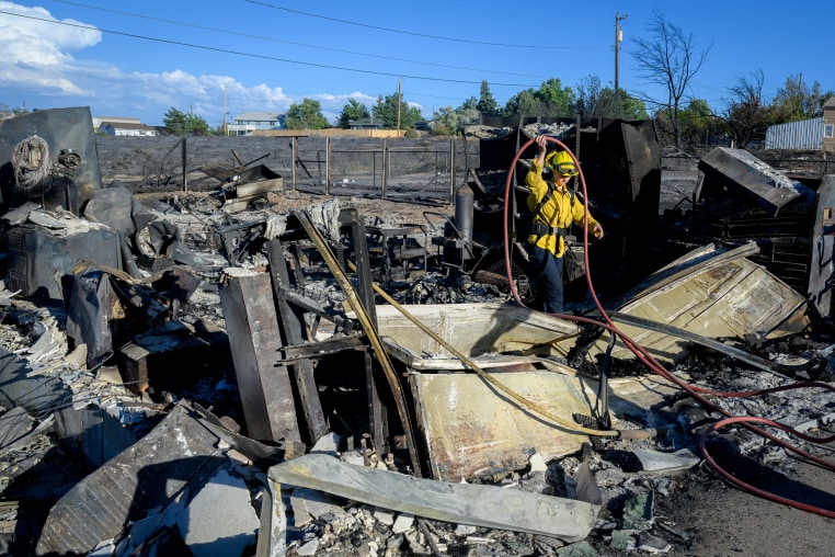 A firefighter works on the remains of a home burned by the Hawk Fire.