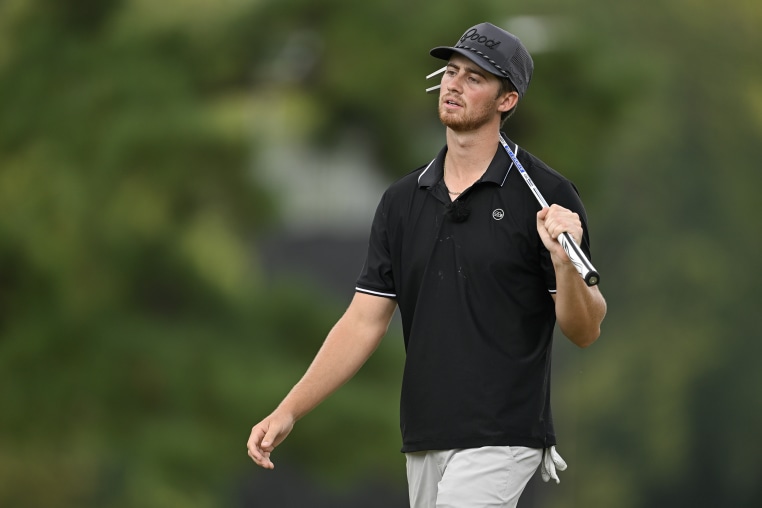 Garrett Clark walks with a golf club over his shoulder.